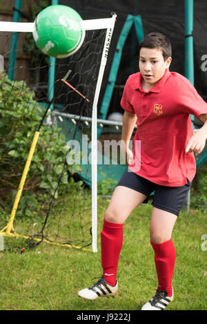 Junge Praktiken Fußball in einen englischen Garten Stockfoto