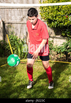 Junge Praktiken Fußball in einen englischen Garten Stockfoto