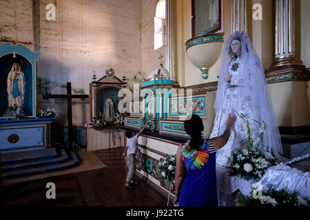 Eine philippinische Frau mit ihrem Sohn besucht die katholische San Isidro Labrador Pfarrkirche umgangsprachlich Lazi Kirche auf die Insel Siquijor befindet sich in der Region Central Visayas auf den Philippinen Stockfoto