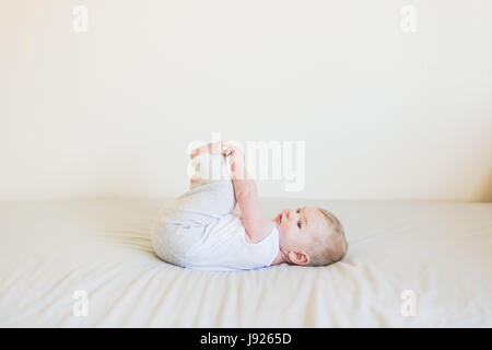 Vier Monate altes Baby junge neugierig mit seinen Zehen drinnen spielen Stockfoto