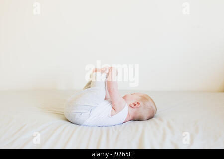 Vier Monate altes Baby junge neugierig mit seinen Zehen drinnen spielen Stockfoto