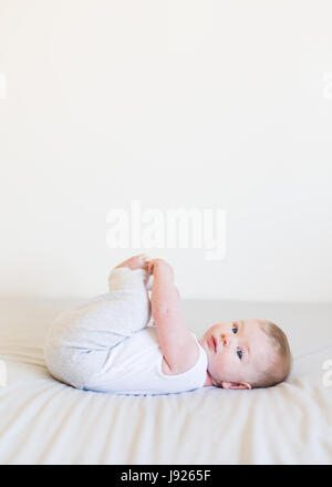 Vier Monate altes Baby junge neugierig mit seinen Zehen drinnen spielen Stockfoto