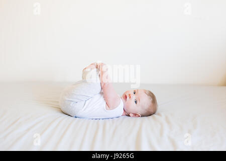 Vier Monate altes Baby junge neugierig mit seinen Zehen drinnen spielen Stockfoto