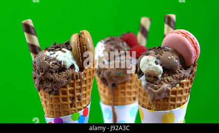 Gourmet Schokolade-Eis mit Makronen Beeren und Früchte vor einem grünen Hintergrund dekoriert. Stockfoto