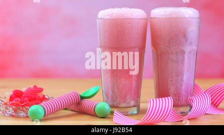 Machen Eis Soda mit rosa Himbeerlimonade und Eis in hohen Café Gläser gegen eine rosa Thema Sommer Party Backgroud schwimmt, Stockfoto