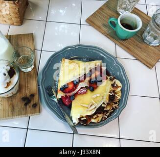 Blaubeere und Erdbeere Krepp Kuchen, Krepp-Bananen-Kuchen mit Kaffee auf graue Schale, Tabellenhintergrund, Ansicht von oben. Stockfoto