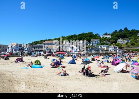 Urlauber entspannen am Strand mit Stadtgebäude nach hinten, Lyme Regis, Dorset, England, Vereinigtes Königreich, West-Europa. Stockfoto