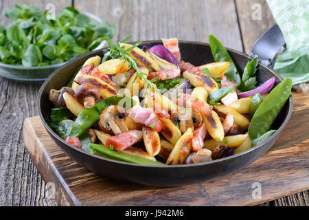 Bayerischen fingerförmige Bratkartoffeln Knödel mit Gemüse und geräuchertem Speck, Feldsalat als einem Beilagensalat Stockfoto