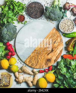 Essen gesunde Kochzutaten zu reinigen. Gemüse, Obst, Bohnen, Körner, grünen Gewürze auf grauem Hintergrund, leere Marmor und Holzbrett in Prozent Stockfoto