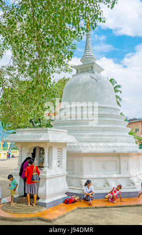 PERADENIYA, SRI LANKA - 28. November 2016: der Stupa von Gatambe Sri Rajopawanaramaya Temple, brachte der Diener Blumen auf dem Altar am November Stockfoto