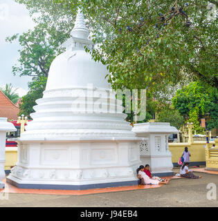 PERADENIYA, SRI LANKA - 28. November 2016: Gemeindemitglieder sitzen am Fuße des kleinen Dagoba Gatambe Sri Rajopawanaramaya Tempel in Peradeniya auf Nove Stockfoto