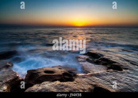 Ein Sonnenaufgang Aufnahme im Washington Eichen Gärten State Park in Palm Coast, FL.  Dies ist auf der Meerseite des Parks.  Die Rock out-Anbau in diesem Bild besteht aus Coquina Felsen, die eine Kombination aus Muscheln und Sand zusammen mit Calcit verbunden ist.  Dieser Stein wurde für den Bau in der Gegend seit Jahrhunderten verwendet.  Washington Eichen Gardens State Park liegt südlich von St. Augustine in der Stadt von Palm Coast.  Das Anwesen war einst im Besitz ein entfernter Verwandter von George Washington.  Die Gärten, gelegen zwischen der Küste und den Fluss Mantanzas wurden von Louise und Owen gegründet. Stockfoto