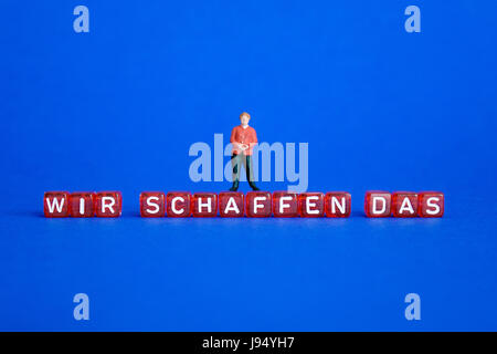 ILLUSTRATION - steht eine kleine Figur von Bundeskanzlerin Angela Merkel am Anfang Buchstaben-Würfel buchstabieren: "WIR SCHAFFEN DAS" (wir können es tun). Genommen 18.03.2017. Dieses Zitat stammt aus einer Pressekonferenz mit Angela Merkel am 31. August 2015, dass sie im Hinblick auf die Flüchtlingskrise in Europa Anfang 2015 und Deutschlands Unterbringung von Flüchtlingen gemacht. Seitdem hat es weitreichende Resonanz in politischen Debatten und in den Medien gefunden. Es ist das zentrale Motto des sogenannten "Willkommenskultur" (Willkommenskultur). Merkel wiederholte die oft kritisierte Satz mehrmals. Stockfoto