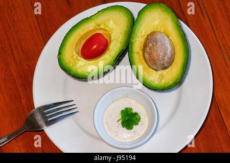 Avocado Birne in zwei Hälften, mit Tomaten und Aioli Sauce Stockfoto