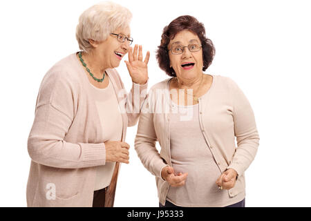 Reife Frau flüstert Freundin überrascht isoliert auf weißem Hintergrund Stockfoto