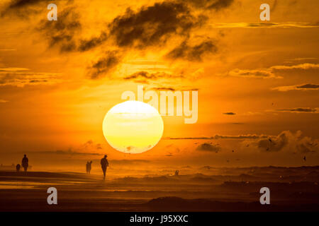 South Carolina, USA. 5. Juni 2017. Menschen am Strand, die Silhouette von der aufgehenden Sonne an einem bewölkten Morgen 5. Juni 2017 in Folly Beach, South Carolina. Folly Beach ist eine schrullige Strandgemeinde außerhalb Charleston Einheimischen als Edge of America bekannt. Bildnachweis: Planetpix/Alamy Live-Nachrichten Stockfoto