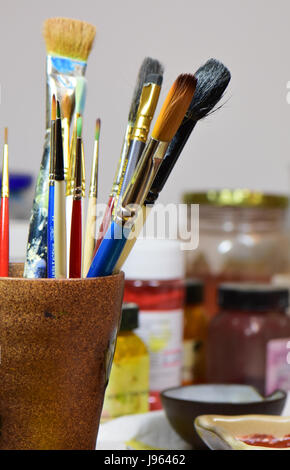 Gläser von Farbe im Hintergrund hinter bunten Pinsel. Stockfoto