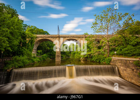 Ein Damm am Wissahickon Creek und der alten Eisenbahnbrücke in Philadelphia, Pennsylvania. Stockfoto