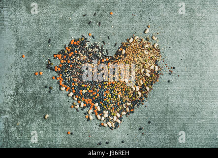 Verschiedene rohe Getreide, Bohnen und Getreide in Form von Herzen Stockfoto