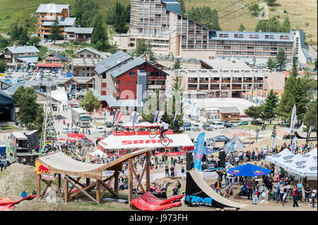 Mann springt mit seinem MTB während einer Freeride World Tour Meisterschaft in Frankreich vor einem Zuschauer (hier im Dorf von "Deux Alpes") Stockfoto