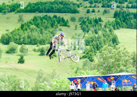 Mann springt mit seinem MTB während einer Freeride World Tour-Meisterschaft in Frankreich (hier im Dorf von "Deux Alpes") Stockfoto