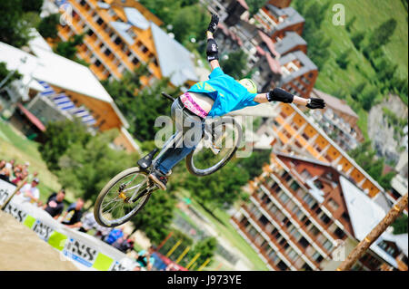 Mann springt mit seinem MTB während einer Freeride World Tour-Meisterschaft in Frankreich (hier im Dorf von "Deux Alpes") Stockfoto