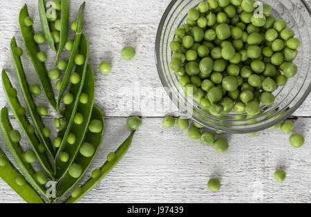 Grüne Erbsen, frisch gepflückt, auf hölzernen Hintergrund angeordnet. Ansicht von oben Stockfoto