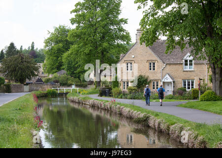 Touristen zu Fuß durch das hübsche Dorf von Lower Slaughter in Gloucestershire Stockfoto