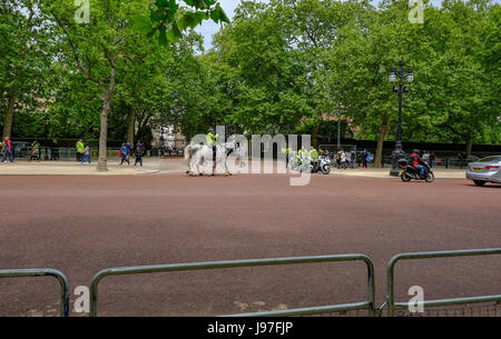 London, UK - 21. Mai 2017: Metropolitan Police auf dem Pferderücken und Motorräder außerhalb der königlichen Residenz in The Mall. Geländer und Straße im Vordergrund. Stockfoto