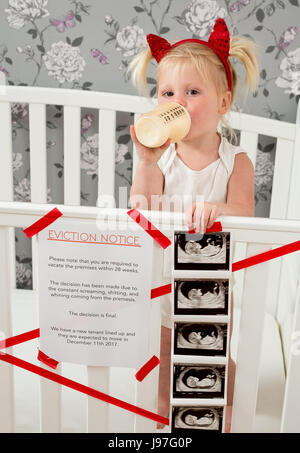 Lustige baby Ankündigung. Ein Kind stand auf, Babybett mit einem lustigen Vertreibung Nachricht an der Seite. Stockfoto