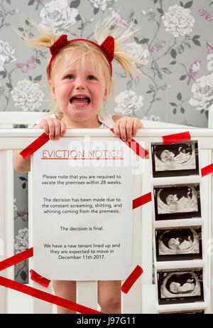 Lustige baby Ankündigung. Ein Kind stand auf, Babybett mit einem lustigen Vertreibung Nachricht an der Seite. Stockfoto