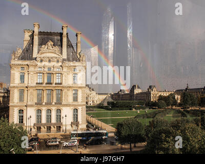 Ein Regenbogen leuchtet über La Louvre Museum nach einem Regen Sturm über Paris, Frankreich. Der Regenbogen symbolisiert Hoffnung. Stockfoto