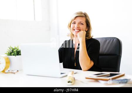 Porträt von Reife Frau im Büro mit Hand am Kinn Stockfoto