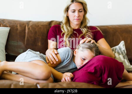 Frau sitzt mit Tochter (6-7) auf couch Stockfoto