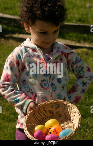 Kleines Mädchen stolz auf ihren Korb gefundene Eier in Easter Egg hunt Stockfoto