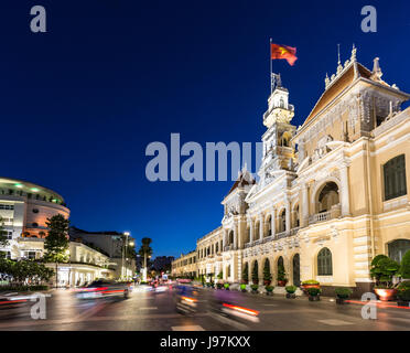 Motorräder in der Nacht vor der berühmten Volkskomitee Gebäude im Herzen der Innenstadt von Ho Chi Minh in Vietnam größte Stadt hetzen, Stockfoto