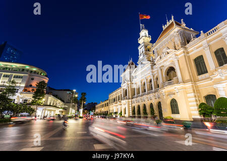 Motorräder in der Nacht vor der berühmten Volkskomitee Gebäude im Herzen der Innenstadt von Ho Chi Minh in Vietnam größte Stadt hetzen, Stockfoto