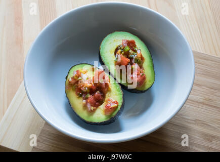 Avocado und Salsa Fresca in einer kleinen weißen Schüssel auf einem Holztisch Stockfoto