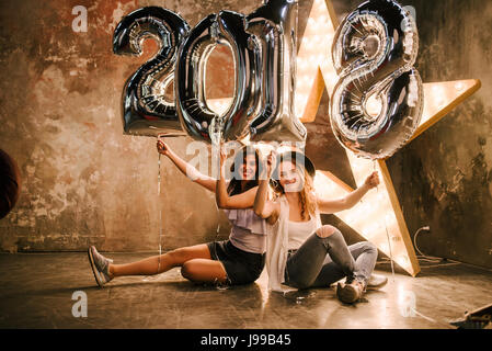 Zwei junge Freundin feiert die 2018 mit großen Ballons, die 2018 auf Kino Retro-Hintergrund bildet Stockfoto