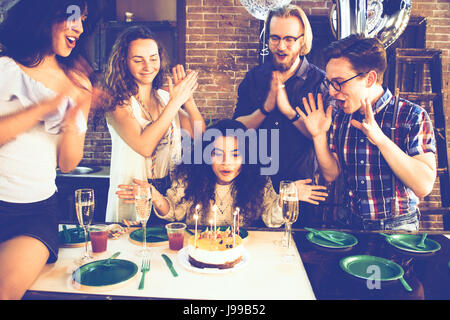 Junges Mädchen feiert ihren Geburtstag Ausblasen der Kerzen mit ihren Freunden Fackel verwendet, um die Stimmung und die Töne der Komposition zu erhöhen Stockfoto