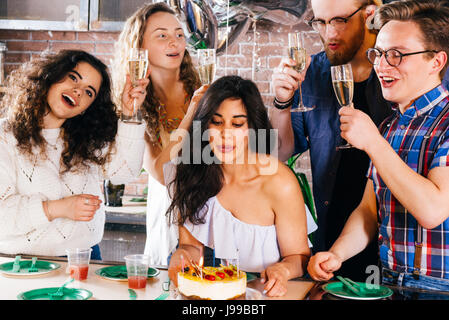 Junges Mädchen feiert ihren Geburtstag mit ihren Freunden den Kerzen ausblasen Stockfoto