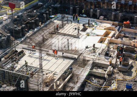 Bauarbeiter pour Beton in Schalung erstellen Sie die Grundlage eines mehrstöckigen Stahl und Beton Gebäude. Stockfoto