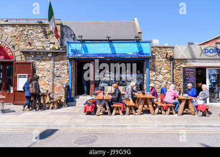 Menschen Essen und genießen Sie einen Drink in der Sonne vor einem Fischrestaurant in Howth, Dublin, Irland. Stockfoto