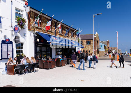 Menschen Essen und genießen Sie einen Drink in der Sonne vor einem Fischrestaurant in Howth, Dublin, Irland. Stockfoto