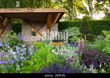 Ein Aufstand der farbenfrohen Pflanzen vor einem Stein und Eiche Loggia im The Morgan Stanley Garten entworfen von Chris Beardshaw bei der RHS Chelsea Flower Show Stockfoto