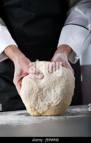 Koch, Teig zu kneten, so dass Teig von männlichen Händen in Bäckerei Stockfoto