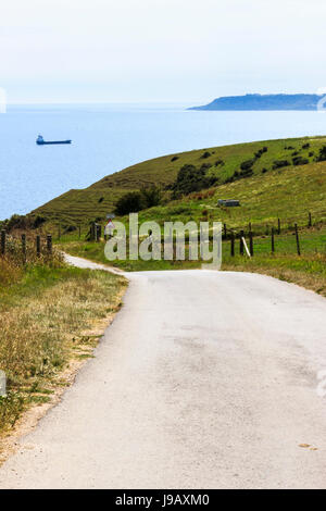 Kurvenreiche Straße hinunter zum Meer und Ringstead Bay, Dorset, England, UK, Portland Bill in der Ferne Stockfoto