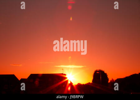 Red Sunset auf einem fast wolkenlosen Himmel mit Sonne Flair auf der Linse, die eine warme Atmosphäre zu schaffen. Stockfoto