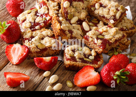 Energiereiche Nahrung: Haferflocken Bars mit Erdbeere, Kürbis Samen und Erdnüssen close-up auf dem Tisch. horizontale Stockfoto