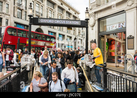 Ein vielbeschäftigter Zeitungshändler von Evening Standard, der von Pendlern an der U-Bahnstation Oxford Circus, London, England, Großbritannien, umgeben ist Stockfoto